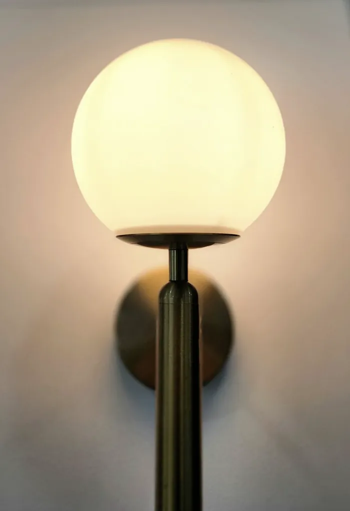 A brass globe wall sconce glowing warmly