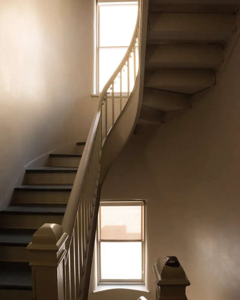 Warm golden hour light falling across a curved plaster staircase